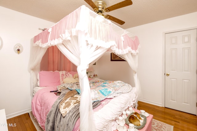 bedroom with hardwood / wood-style floors, a textured ceiling, and ceiling fan