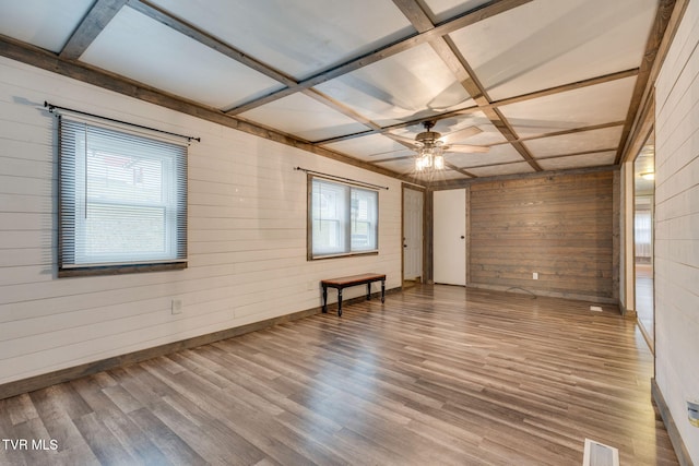 spare room with hardwood / wood-style flooring, coffered ceiling, wooden walls, and ceiling fan