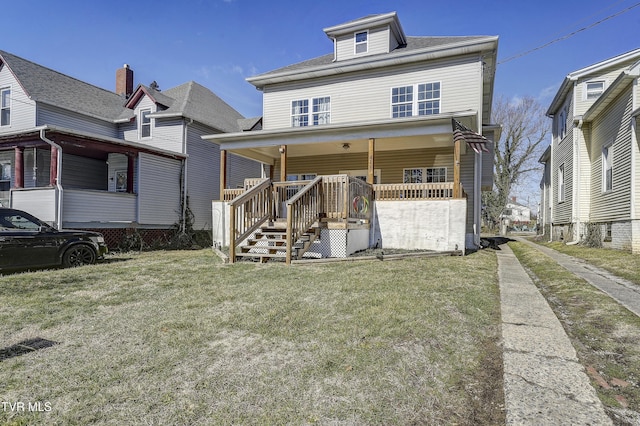 rear view of house featuring a lawn and covered porch