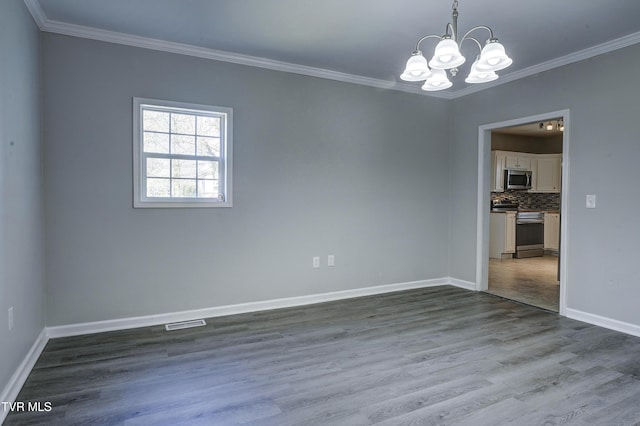 spare room featuring hardwood / wood-style floors, crown molding, and a notable chandelier