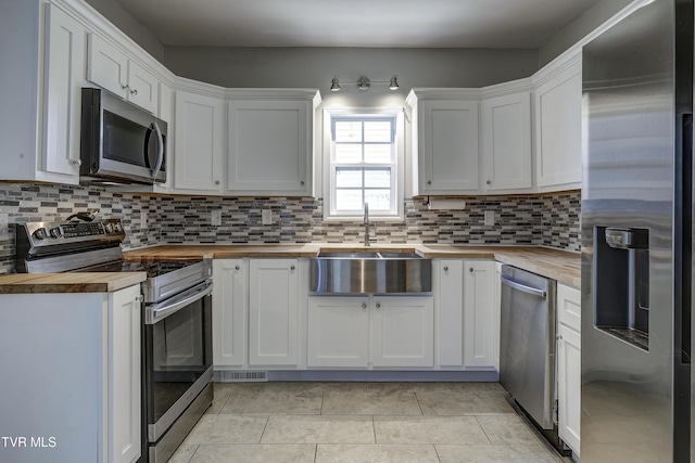 kitchen featuring white cabinetry, wood counters, stainless steel appliances, and sink