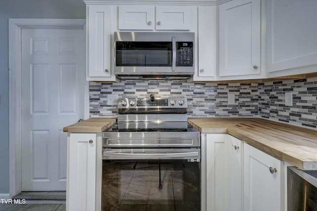 kitchen with appliances with stainless steel finishes, butcher block counters, decorative backsplash, and white cabinets