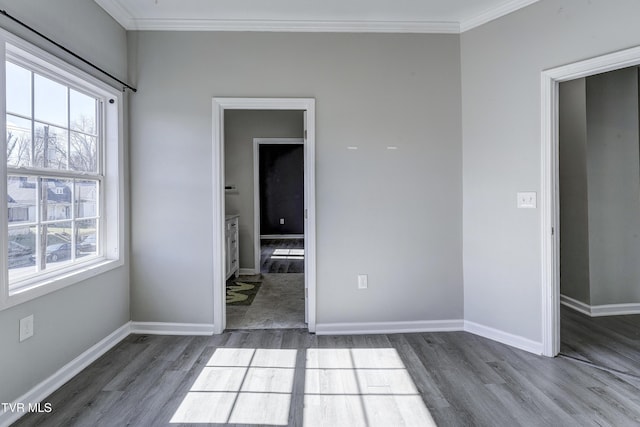 spare room featuring crown molding, wood-type flooring, and a wealth of natural light