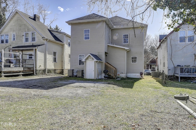 rear view of house with a wooden deck, a storage shed, a yard, and central AC