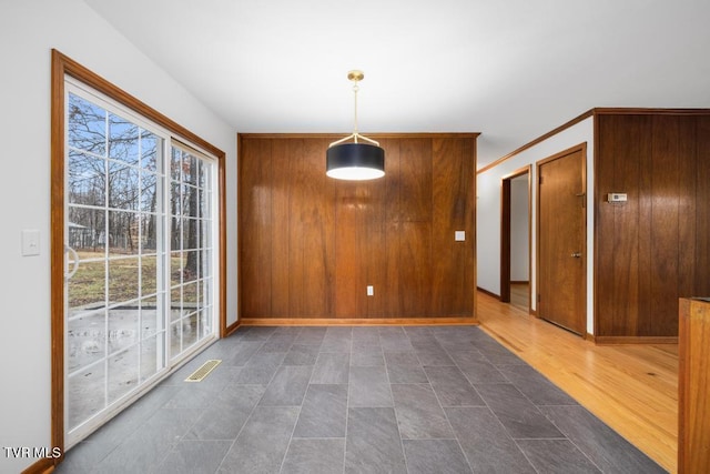 unfurnished dining area featuring plenty of natural light, dark hardwood / wood-style floors, and wooden walls