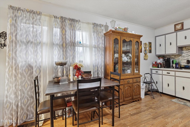 dining space featuring light hardwood / wood-style flooring and a textured ceiling