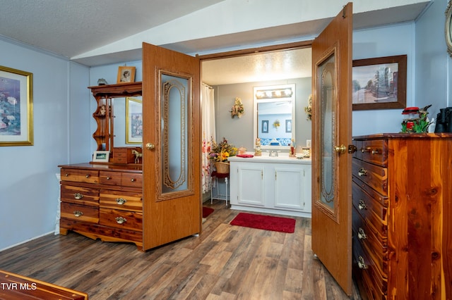 bathroom featuring vanity, hardwood / wood-style floors, vaulted ceiling, and a textured ceiling