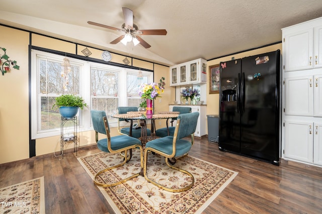 dining area featuring vaulted ceiling, ceiling fan, a textured ceiling, and dark hardwood / wood-style flooring