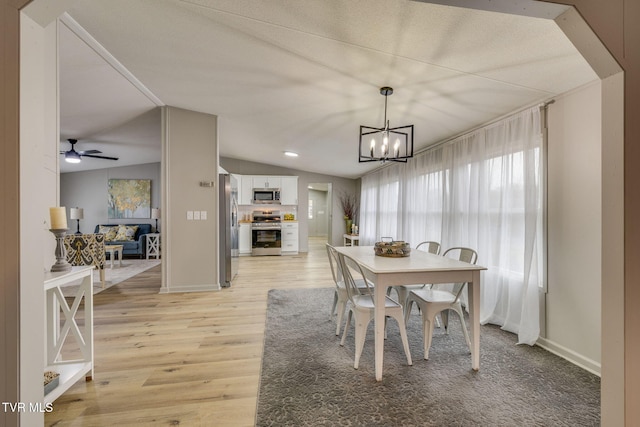 dining room featuring lofted ceiling, ceiling fan with notable chandelier, and light wood-type flooring