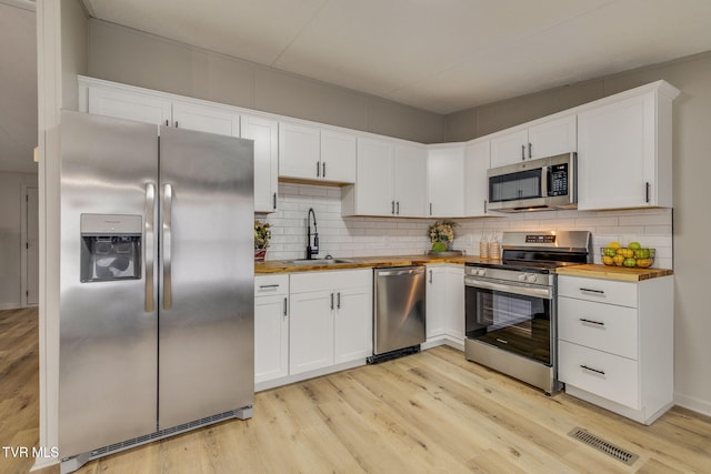 kitchen featuring white cabinets, appliances with stainless steel finishes, sink, and wooden counters