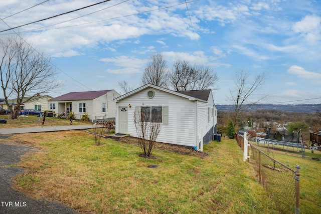 view of front of house featuring cooling unit, a trampoline, and a front yard