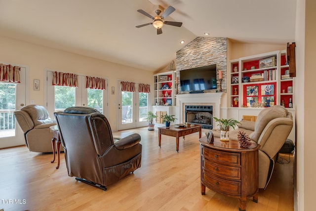 living room featuring high vaulted ceiling, a large fireplace, ceiling fan, and light hardwood / wood-style flooring