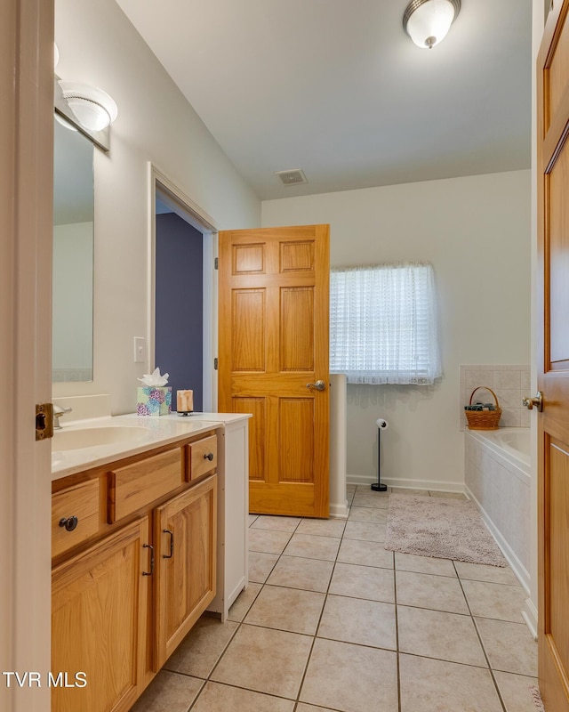 bathroom featuring tile patterned floors, vanity, and tiled tub