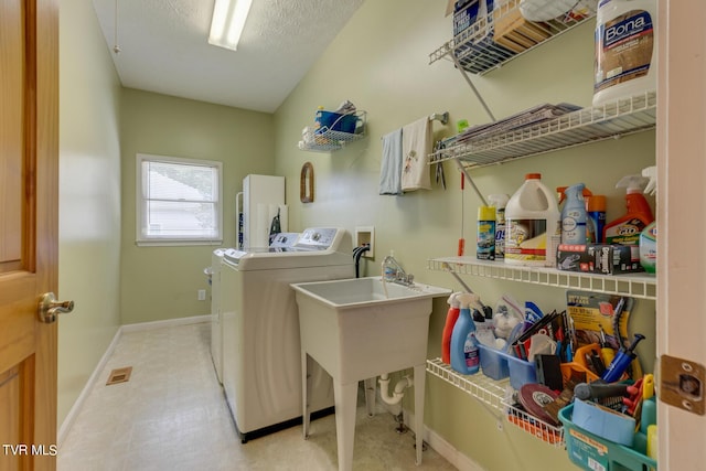 laundry area with independent washer and dryer and a textured ceiling