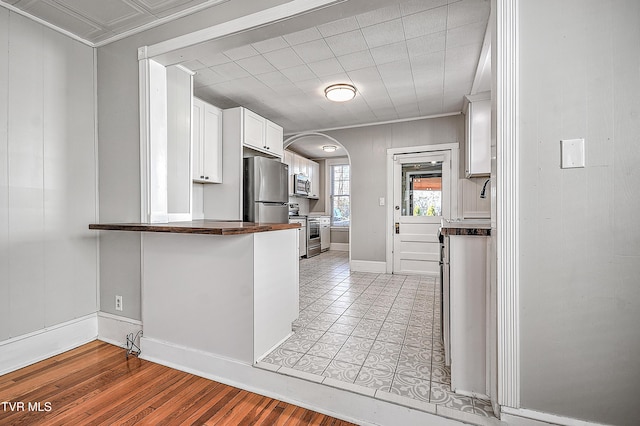 kitchen with white cabinetry, appliances with stainless steel finishes, light wood-type flooring, and kitchen peninsula