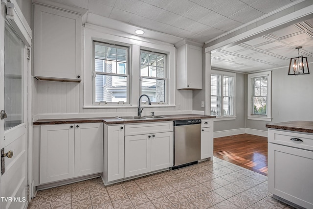 kitchen with sink, light tile patterned floors, dishwasher, hanging light fixtures, and white cabinets