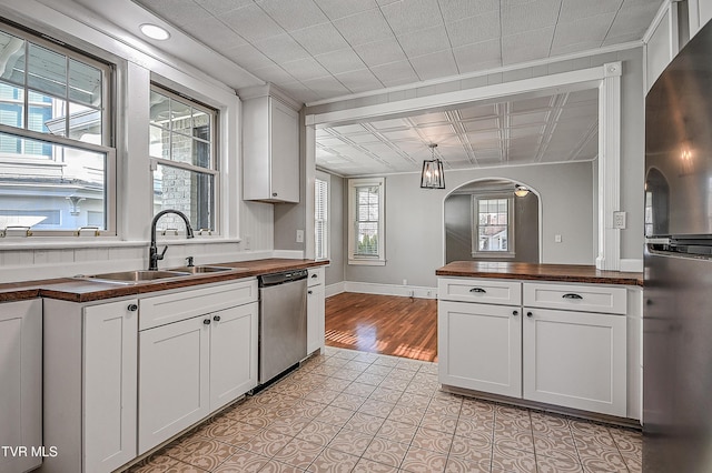 kitchen with sink, white cabinetry, wooden counters, hanging light fixtures, and appliances with stainless steel finishes