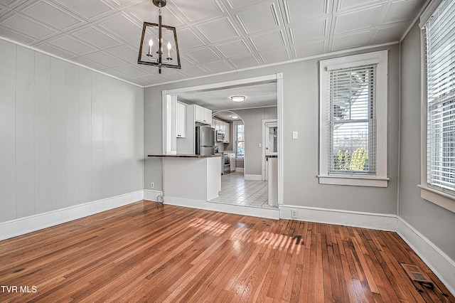 unfurnished living room with a notable chandelier and light hardwood / wood-style floors