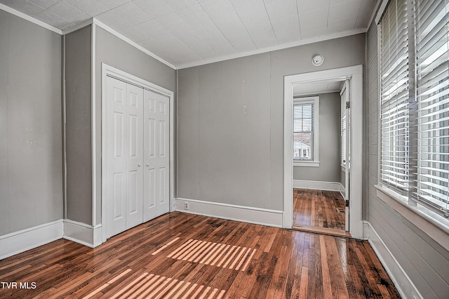 unfurnished bedroom with crown molding, dark hardwood / wood-style flooring, and a closet