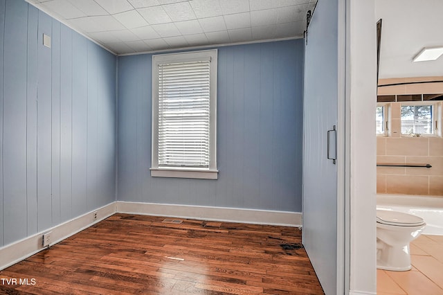 unfurnished room with dark hardwood / wood-style floors and a barn door