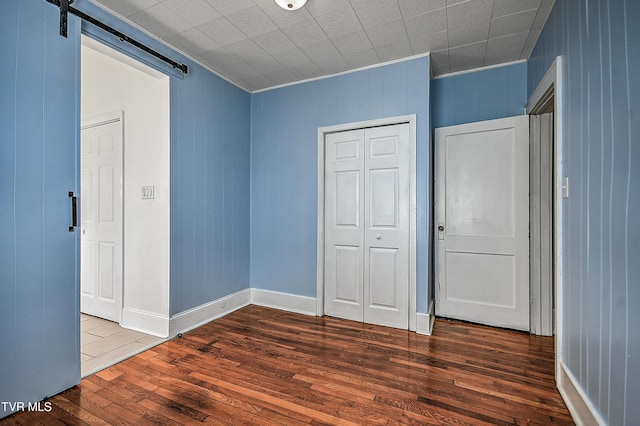 unfurnished bedroom with a closet, hardwood / wood-style flooring, and a barn door