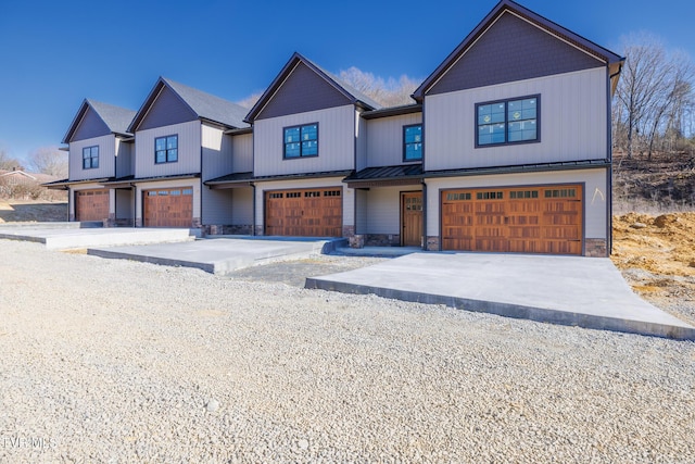 modern farmhouse style home with stone siding, a standing seam roof, driveway, and an attached garage