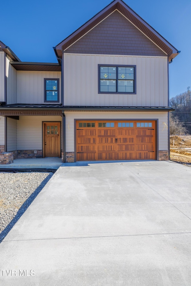 view of front facade with a garage, stone siding, board and batten siding, and concrete driveway