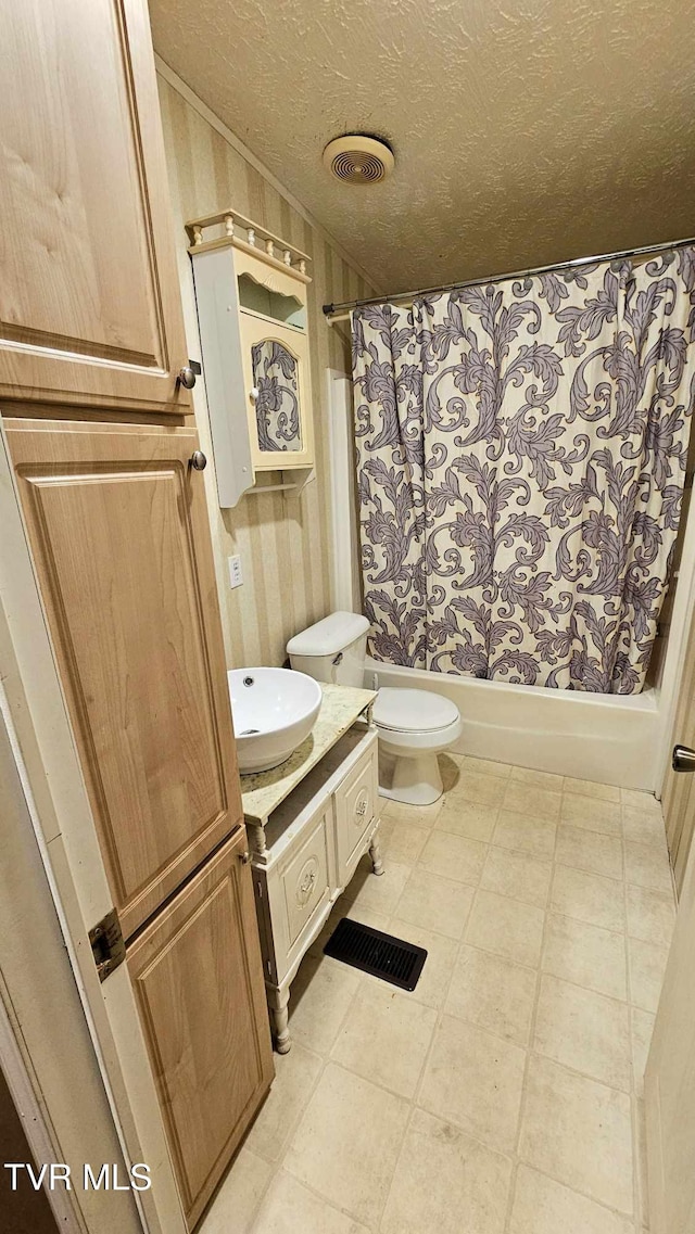 full bathroom featuring vanity, toilet, a textured ceiling, and shower / bath combo