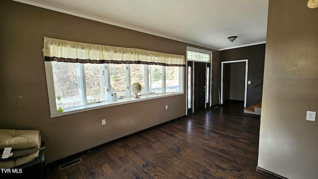 empty room featuring crown molding, dark hardwood / wood-style floors, and a textured ceiling