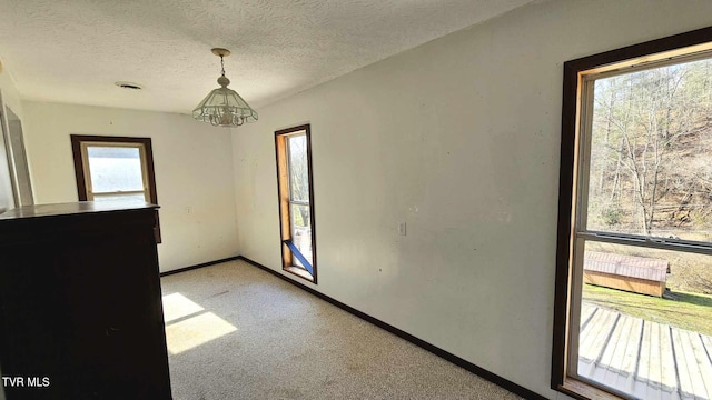 spare room featuring a chandelier, light carpet, and a textured ceiling