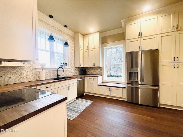 kitchen with pendant lighting, sink, butcher block countertops, appliances with stainless steel finishes, and dark hardwood / wood-style floors