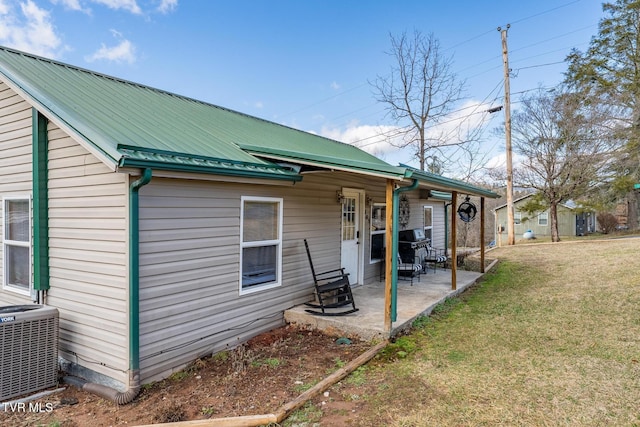 rear view of house with central AC unit, a yard, and a patio area