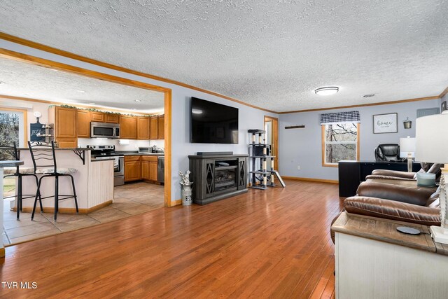 living room featuring crown molding, a textured ceiling, and light wood-type flooring