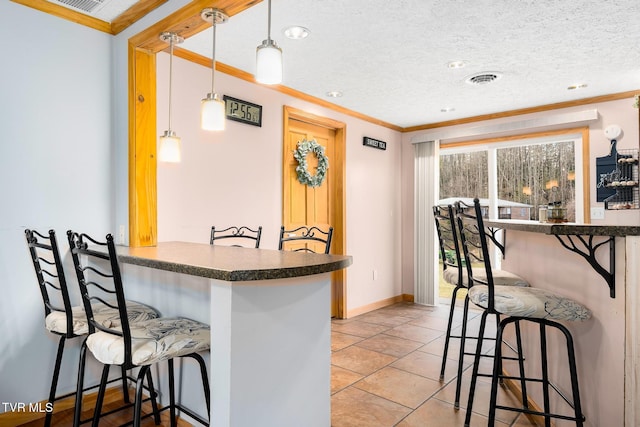 kitchen with hanging light fixtures, crown molding, a breakfast bar area, and kitchen peninsula