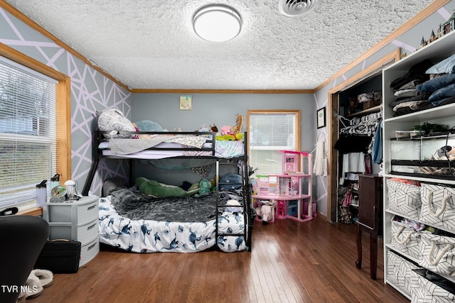 bedroom featuring ornamental molding, dark hardwood / wood-style floors, and a textured ceiling