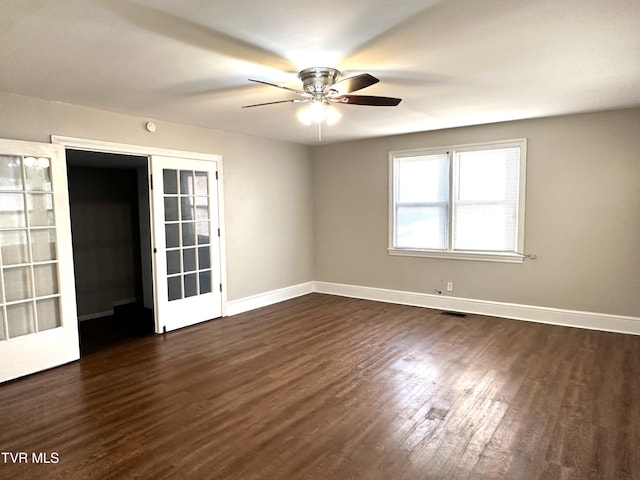 empty room featuring a ceiling fan, dark wood-type flooring, and baseboards