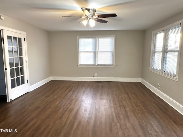 spare room with dark wood-style floors, plenty of natural light, ceiling fan, and baseboards