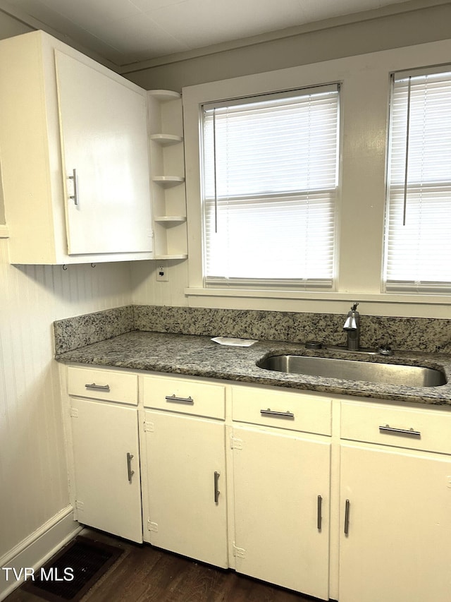 kitchen with a sink, dark stone counters, dark wood-style floors, white cabinetry, and open shelves