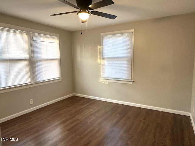 unfurnished room featuring baseboards, dark wood finished floors, and a ceiling fan