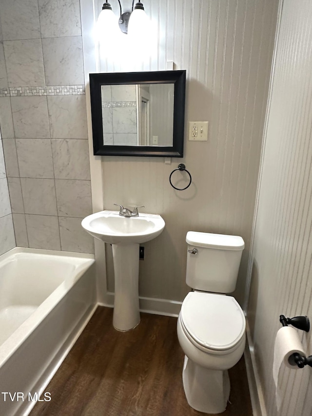 full bathroom featuring baseboards, toilet, wood finished floors, and bathing tub / shower combination