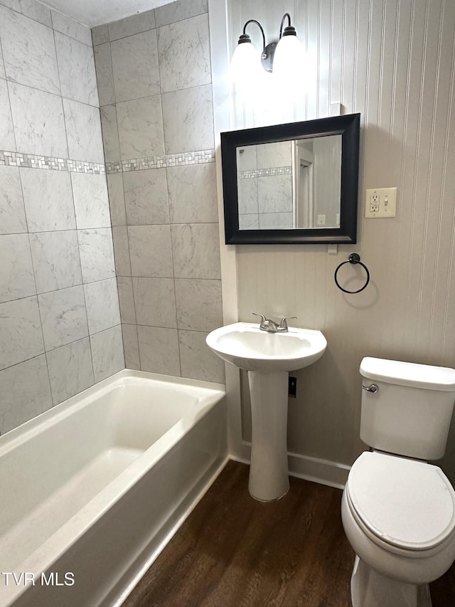 bathroom featuring wood finished floors, baseboards, a sink, toilet, and shower / bathtub combination