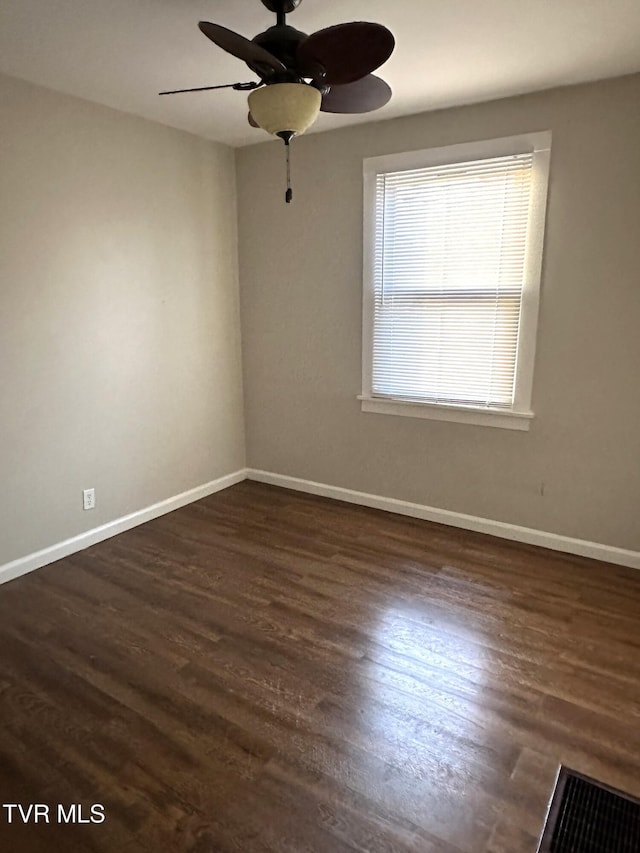 spare room with baseboards, ceiling fan, and dark wood-style flooring