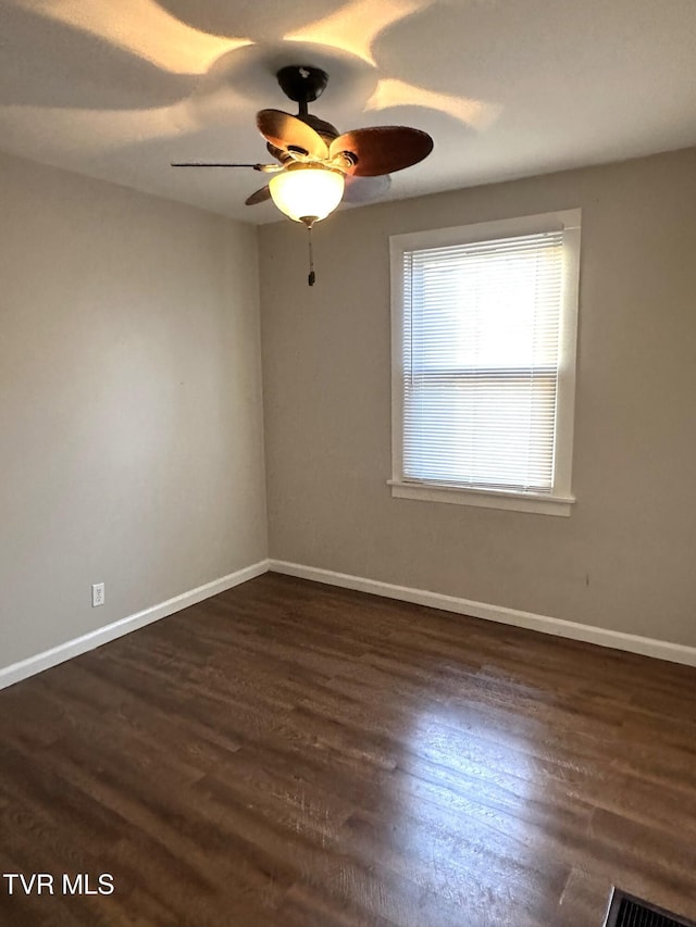 unfurnished room with dark wood finished floors, a ceiling fan, and baseboards