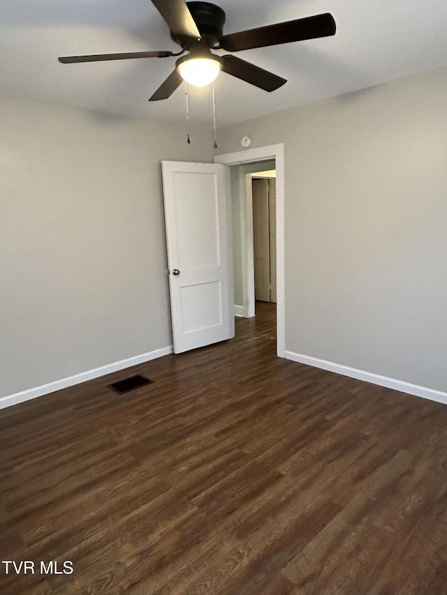 unfurnished room featuring visible vents, baseboards, dark wood finished floors, and a ceiling fan