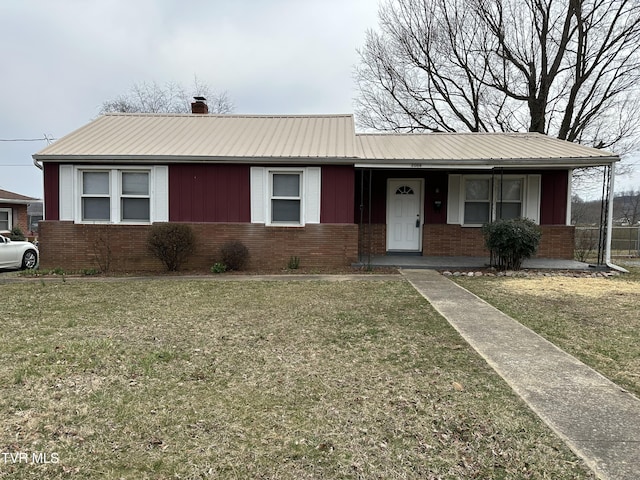 single story home with metal roof, brick siding, covered porch, and a front yard