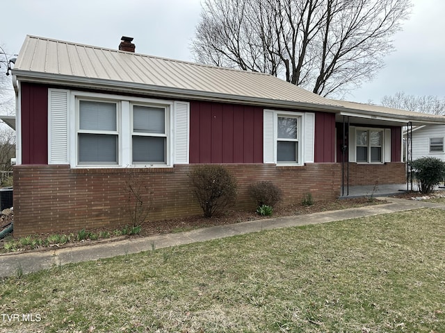 ranch-style house with brick siding, board and batten siding, a front lawn, a chimney, and metal roof