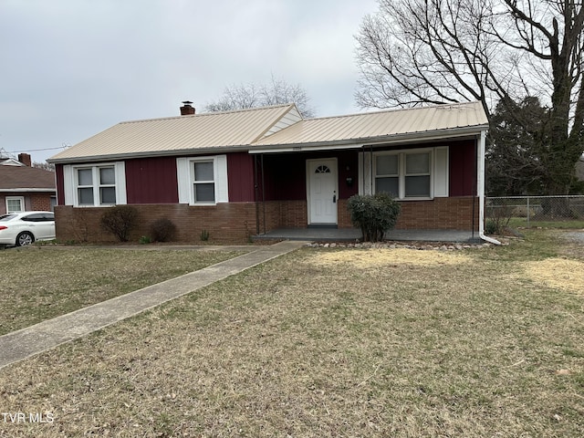 ranch-style house featuring brick siding, metal roof, a front yard, and fence