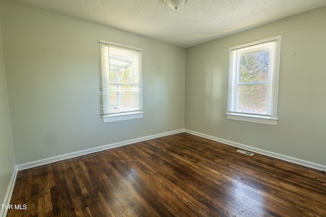 unfurnished room with dark wood-type flooring, a healthy amount of sunlight, visible vents, and a textured ceiling