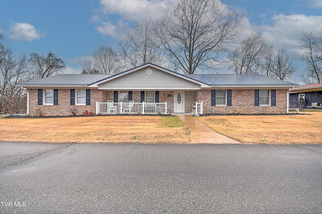 ranch-style house featuring covered porch, brick siding, metal roof, and a front yard