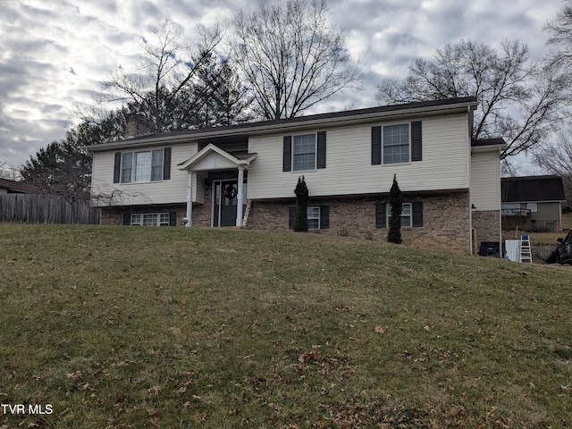 bi-level home with a front lawn, a chimney, and brick siding